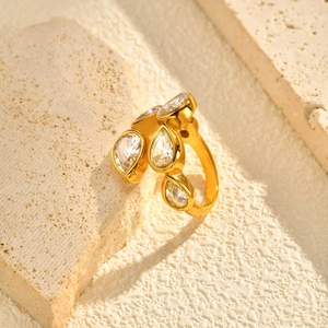 Macro detail of gold stainless steel ring with pear-cut cubic zirconia on stone texture