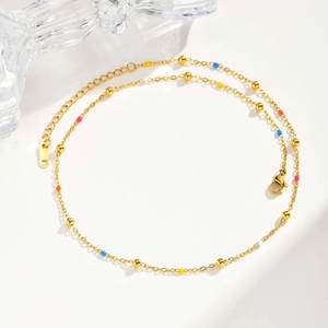 Detail of gold beaded chain with colorful enamel accents and lobster clasp on white texture