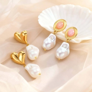 Detail of vintage style earrings with baroque pearls and pink gemstones on shell background