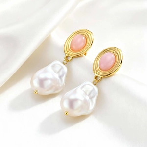 Close-up of vintage gold oval earrings with pink stone and baroque pearl on silk