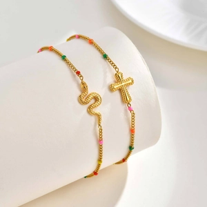Gold stainless steel snake and cross bracelets with colorful beads on a white display