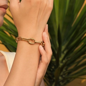 Bracciale a catena in oro acciaio inossidabile con morsetto su sfondo di foglia tropicale