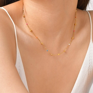 Detailed view of a gold bead necklace with colorful enamel accents on a model's neck