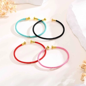 Detail of four colorful woven rope cuffs with golden metal ends on a minimalist background