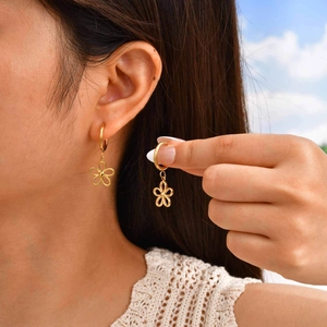 Boucles d'oreilles fleurs dorées en acier inoxydable portées sous un ciel bleu