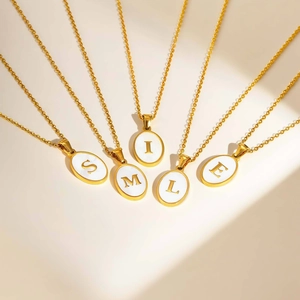 Detailed view of five gold oval pendants spelling SMILE on a white minimalist surface