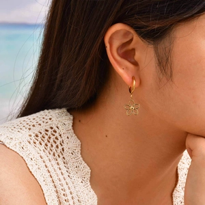 Gros plan d'un mannequin portant des boucles d'oreilles fleurs ajourées au bord de mer