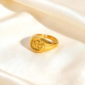 Detail of vintage gold Cupid relief signet ring on elegant silk background