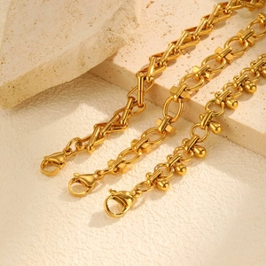 Detailed view of triple gold layered bracelets set with geometric and bead chain charms