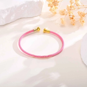 Detail of pink woven rope bracelet featuring golden metal end caps in a minimalist setting