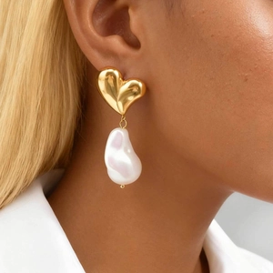 Vintage style gold heart earrings with white baroque pearls shown on a female model