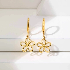 Gros plan détaillé de boucles d'oreilles fleurs évidées en acier doré sur présentoir