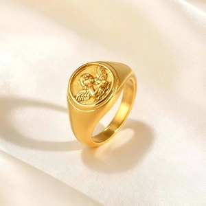 Macro shot of gold stainless steel ring with relief angel seal on champagne silk