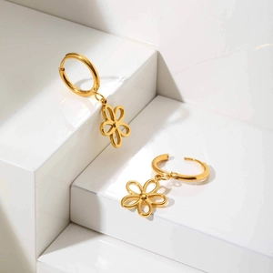 Boucles d'oreilles fleur évidée en or poli sur des marches blanches géométriques