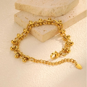 Close-up of golden link bracelet with teardrop charms on stone, K18 hallmark detail