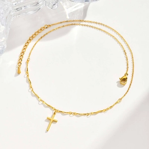 Close-up of gold cross necklace with wavy link chain and adjustable lobster clasp closure