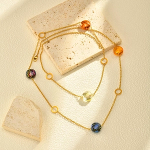 Détail d'un collier doré avec perles de cristal colorées sur décor en pierre