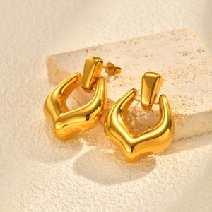 Detailed macro view of 18K gold plated hollow geometric earrings on a stone pedestal