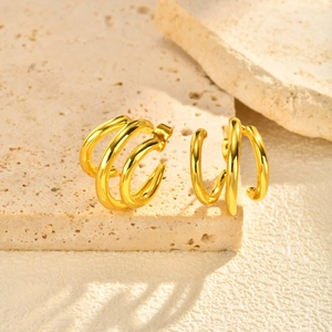 Boucles d'oreilles créoles dorées à trois rangs sur un support en pierre texturée