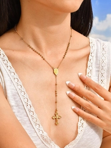 Vue rapprochée d'un collier chapelet doré avec croix et médaille sur un mannequin