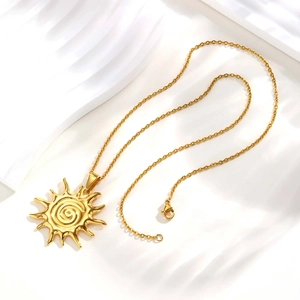 Close-up of 18K gold plated sun pendant necklace with spiral center on white background