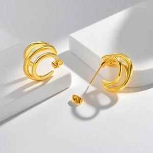 Détail de boucles d'oreilles créoles dorées à trois couches avec finition miroir polie