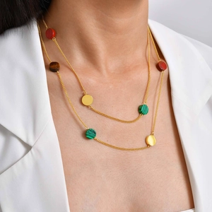 Gros plan du collier double rang doré avec des pendentifs ronds en malachite et pierre