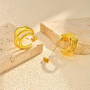 Vue détaillée de boucles d'oreilles dorées en forme de C à trois couches sur pierre