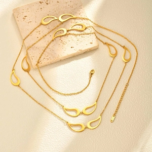 Détail du collier en acier inoxydable doré avec breloques goutte sur socle en marbre
