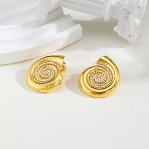 Macro shot of gold spiral conch earrings with white pearls and brushed metal finish