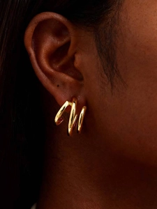 Gros plan de boucles d'oreilles créoles dorées à triple tube sur mannequin avec fini brillant