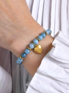 Gros plan détaillé d'un bracelet en perles bleues avec un pendentif cœur doré au poignet