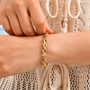 Elegant gold-tone interlocked geometric link chain bracelet on a white knit sleeve