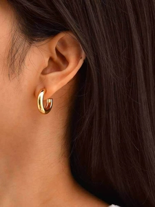 Close-up of elegant gold C-shaped chunky hoop earring worn on a model's ear