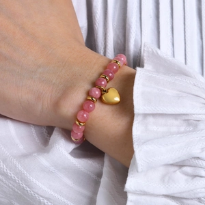 Bracelet élégant en perles roses avec pendentif cœur doré porté sur une manche dentelle