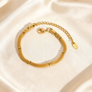 Detailed close-up of woven mesh gold chain bracelet with beads and K18 hallmark tag