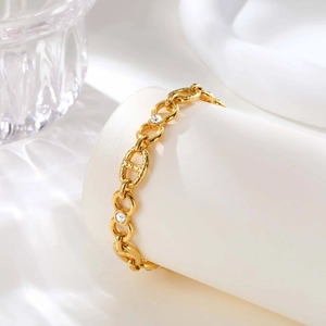 Close-up of gold interlocking chain bracelet with white zircon stones on white silk