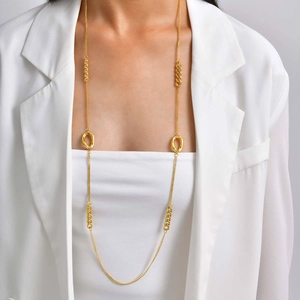Gros plan d'un collier doré avec pendentif cœur et perle porté sur un haut blanc élégant