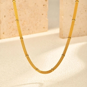 Detailed macro view of golden mesh chain bracelet with elegant gold bead accents