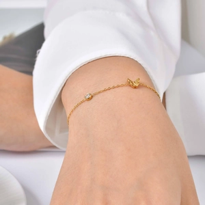 Gros plan du bracelet papillon en or 18K avec un petit zircon sur le poignet d'une femme