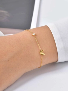 Détail du collier papillon doré avec pendentif en zircon porté au poignet