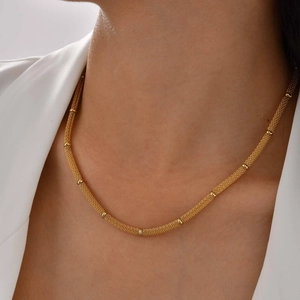 Detailed close-up of golden mesh chain bracelet with spacer beads on a model's wrist