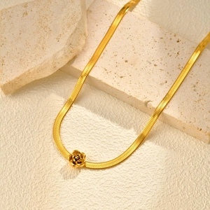 Macro detail of golden stainless steel snake chain with a 3D rose flower pendant