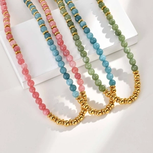 Three elegant beaded necklaces in pink green and blue stone with gold spacers on white stands