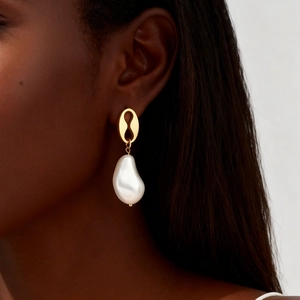 Gros plan d'une boucle d'oreille en perle baroque avec un clou ovale doré sur un mannequin