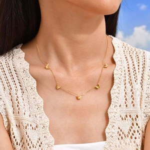 Collier papillon doré avec cinq pendentifs porté sur un haut en crochet blanc