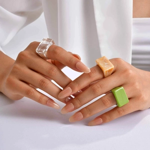 Close-up of minimalist resin rings set in clear, orange marble, and vibrant green colors