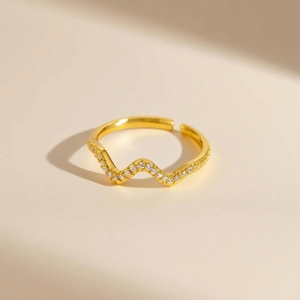 Adjustable golden wave ring with shimmering zircon inlays on a neutral background