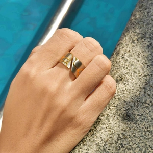 Minimalist bicolor pebble open ring with geometric etching on finger by poolside