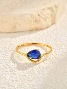 Detail of a pear-cut blue zircon stone on a gold-plated stainless steel ring